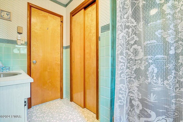 bathroom with tile patterned flooring, vanity, and tile walls