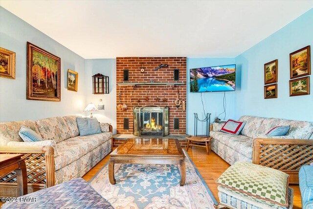 living room with light wood-type flooring and a brick fireplace