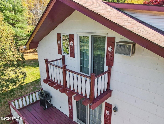 view of exterior entry with a wall mounted air conditioner and a balcony