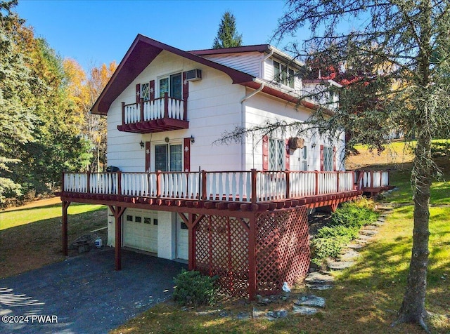 back of property featuring a lawn, a wooden deck, a balcony, and a garage