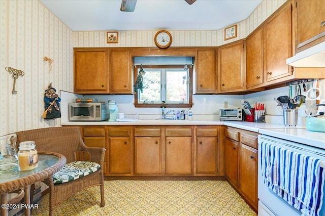 kitchen with ceiling fan, stove, and sink