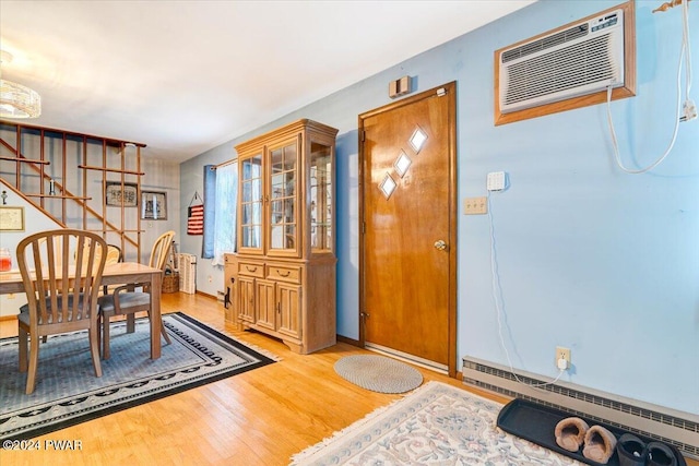 dining space featuring an AC wall unit, a baseboard radiator, and light wood-type flooring