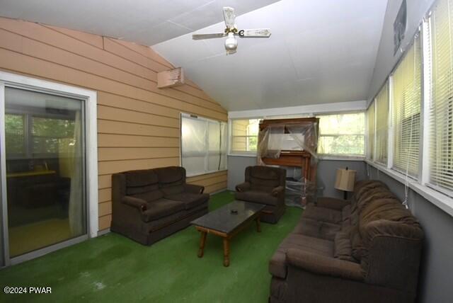 carpeted living room featuring lofted ceiling, plenty of natural light, ceiling fan, and wooden walls