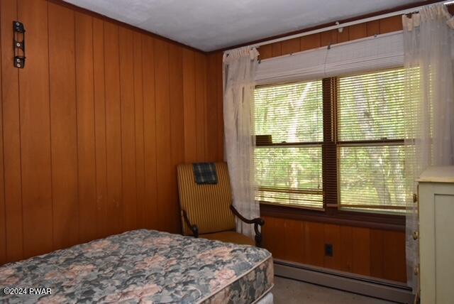 bedroom with wood walls and a baseboard heating unit