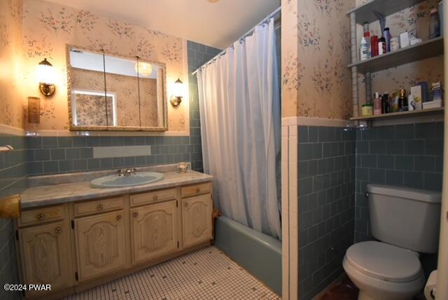 full bathroom with shower / bath combination with curtain, vanity, tile walls, tile patterned flooring, and toilet