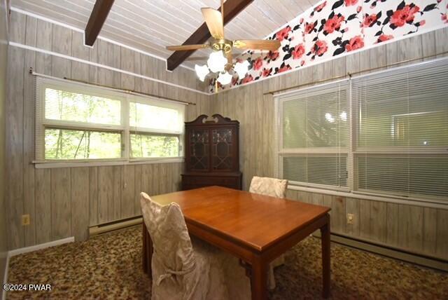 dining area with wood walls, beamed ceiling, a baseboard radiator, and ceiling fan