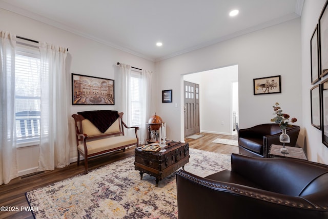 living area with ornamental molding, visible vents, and light wood-style flooring