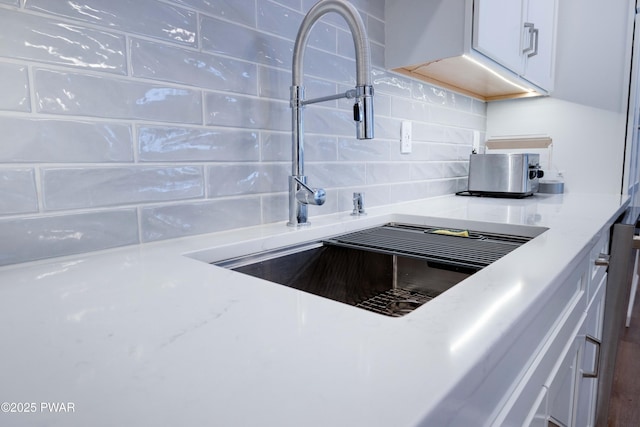 kitchen featuring white cabinets, a sink, and decorative backsplash