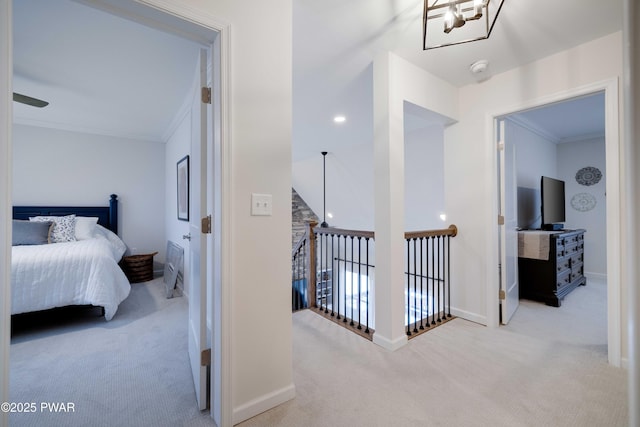 corridor with carpet floors, baseboards, crown molding, and an upstairs landing