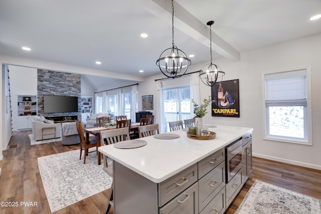 kitchen featuring stainless steel microwave, gray cabinets, dark wood finished floors, and a center island