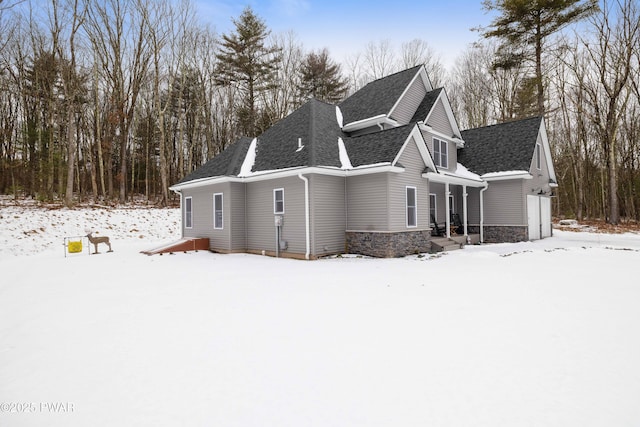 exterior space with a garage, stone siding, and roof with shingles