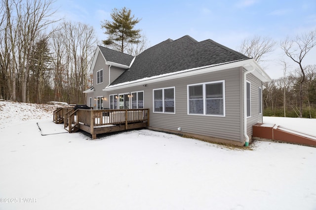 snow covered rear of property featuring roof with shingles and a deck