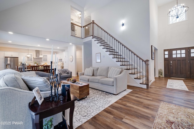 living area with baseboards, stairway, a chandelier, and dark wood-style flooring