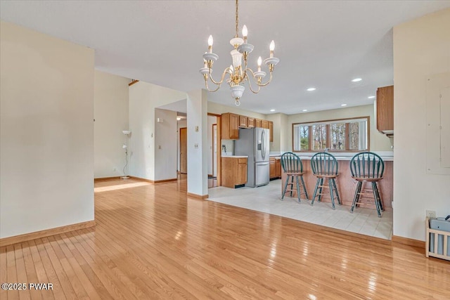 105 Beechwood Ln, Greentown, PA 18426 - kitchen with stainless steel fridge with ice dispenser, light wood-style floors, brown cabinets, and an inviting chandelier