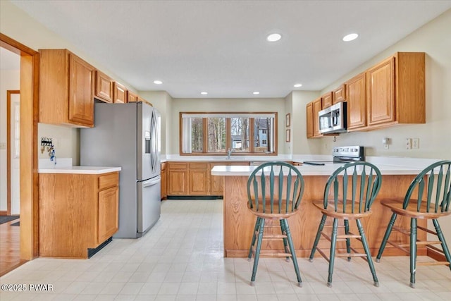 105 Beechwood Ln, Greentown, PA 18426 - kitchen with a peninsula, appliances with stainless steel finishes, a sink, light countertops, and a breakfast bar area