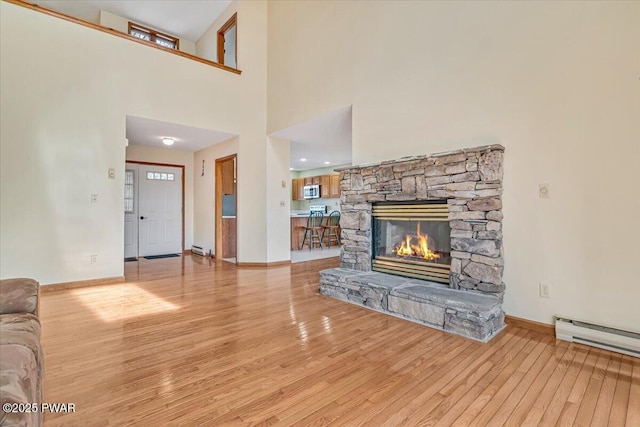 105 Beechwood Ln, Greentown, PA 18426 - unfurnished living room featuring light wood-style flooring, baseboard heating, baseboards, and a stone fireplace