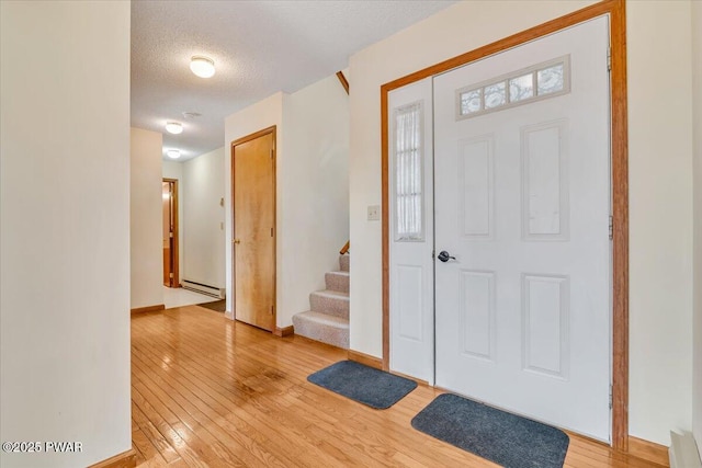 105 Beechwood Ln, Greentown, PA 18426 - foyer featuring stairway, a baseboard radiator, light wood-style flooring, and a textured ceiling