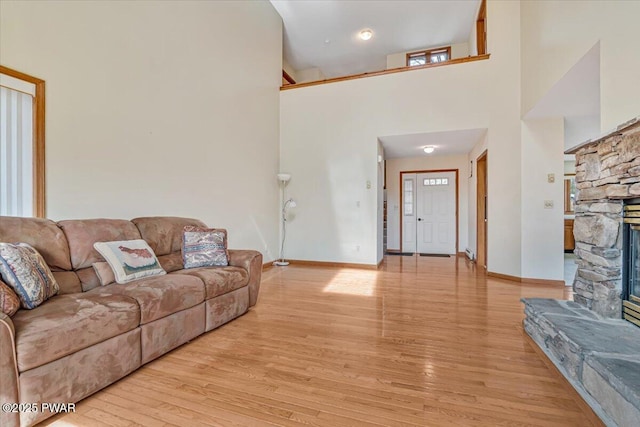 105 Beechwood Ln, Greentown, PA 18426 - living area featuring a stone fireplace, a towering ceiling, light wood-style floors, and baseboards