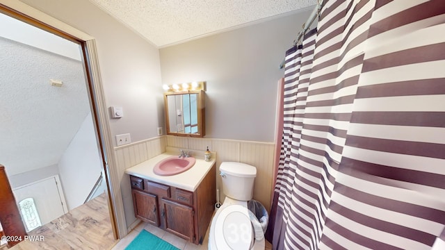 bathroom featuring vanity, a textured ceiling, toilet, and wood walls