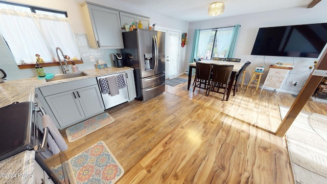 kitchen with gray cabinetry, sink, appliances with stainless steel finishes, and light hardwood / wood-style flooring