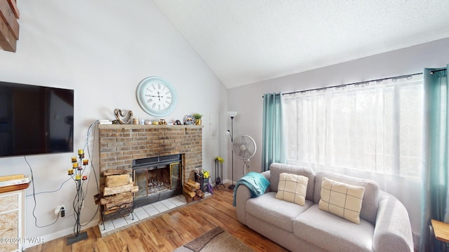 living room featuring hardwood / wood-style floors, lofted ceiling, a textured ceiling, and a brick fireplace