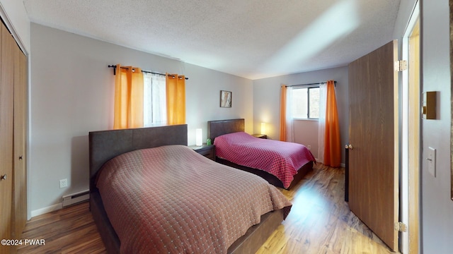 bedroom with hardwood / wood-style floors, a closet, a baseboard radiator, and a textured ceiling