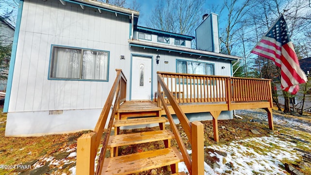 snow covered house with a wooden deck