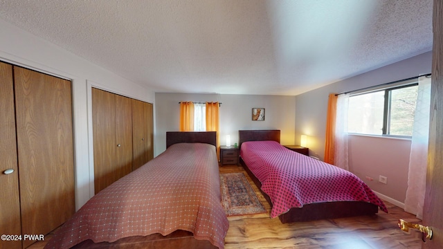 bedroom featuring two closets, a textured ceiling, and multiple windows