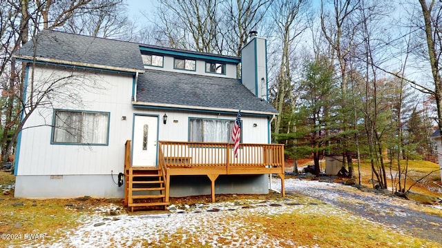 snow covered back of property with a wooden deck