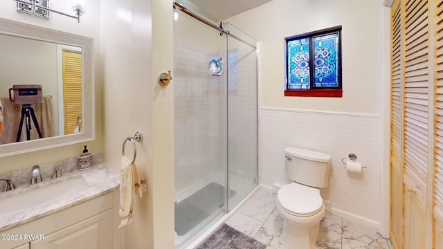 bathroom with tile walls, vanity, an enclosed shower, and toilet