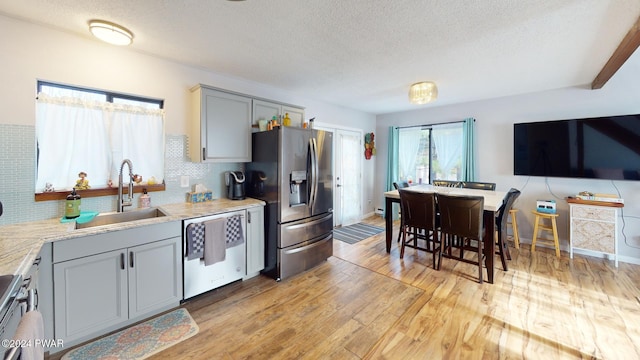 kitchen featuring gray cabinetry, sink, stainless steel appliances, light hardwood / wood-style flooring, and a textured ceiling