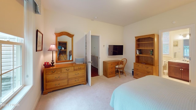 carpeted bedroom featuring ensuite bathroom and sink