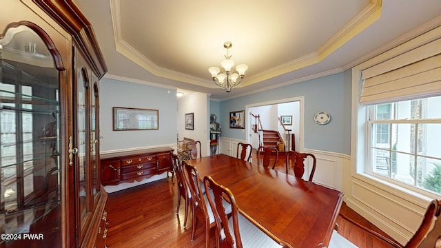 dining space featuring hardwood / wood-style floors, a raised ceiling, crown molding, and a chandelier