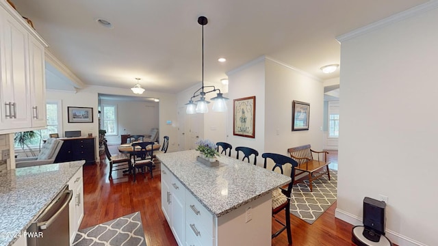 kitchen featuring white cabinetry, a center island, a kitchen breakfast bar, light stone counters, and pendant lighting