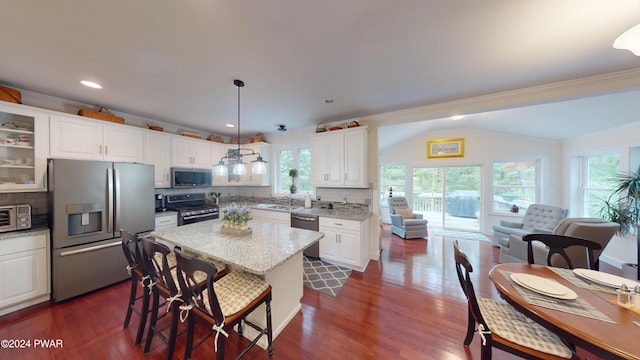 kitchen with light stone countertops, white cabinetry, backsplash, pendant lighting, and appliances with stainless steel finishes