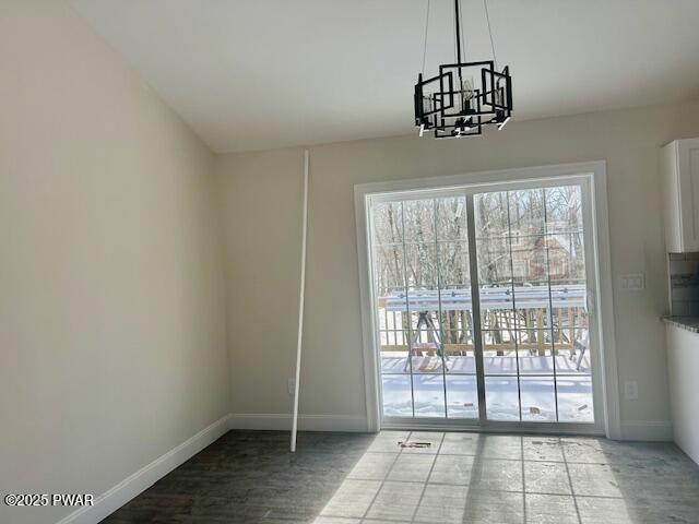 doorway with a chandelier, baseboards, and wood finished floors