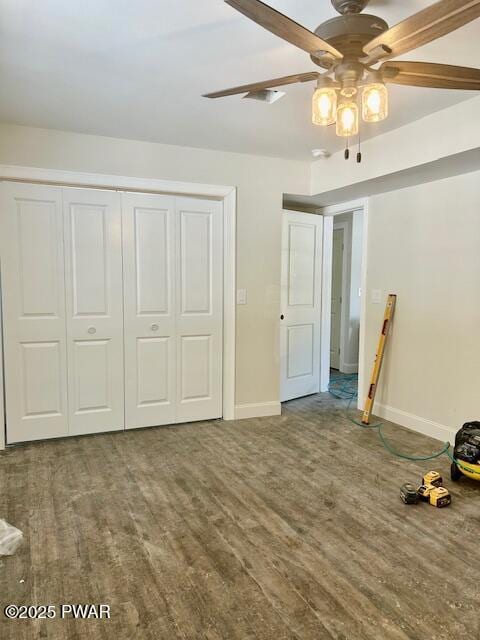 unfurnished bedroom with a ceiling fan, a closet, baseboards, and wood finished floors