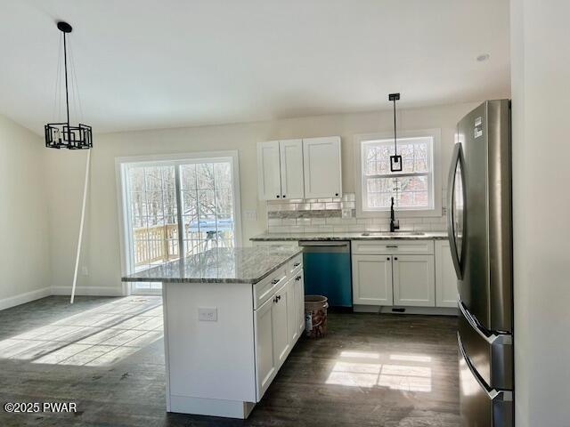 kitchen featuring appliances with stainless steel finishes, pendant lighting, white cabinetry, and a sink