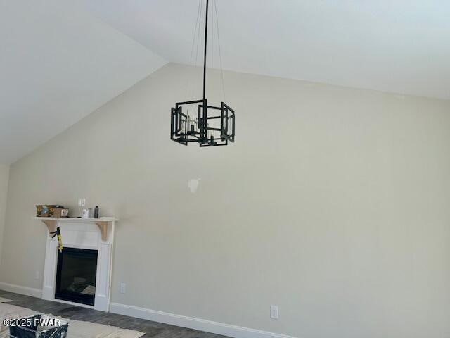 unfurnished living room with a glass covered fireplace, vaulted ceiling, and baseboards