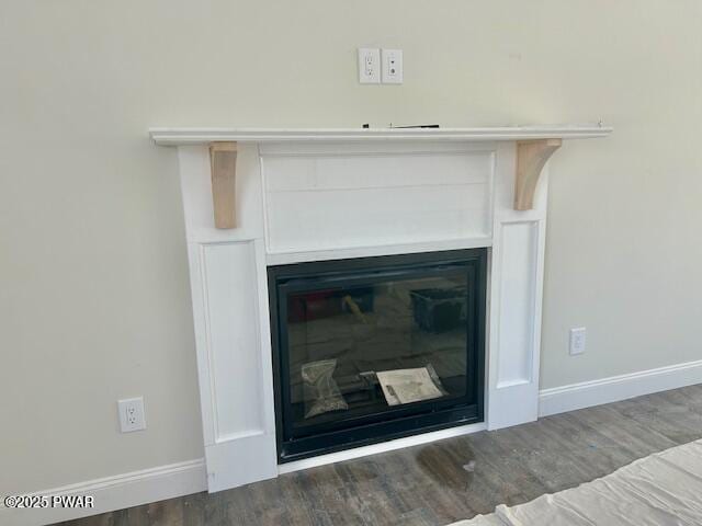 details with baseboards, wood finished floors, and a glass covered fireplace