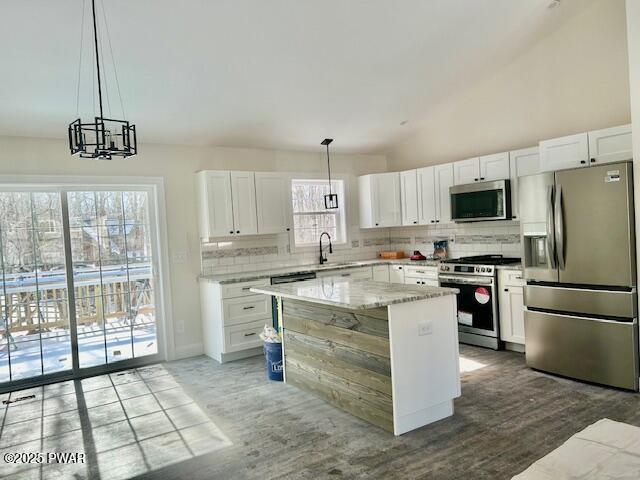 kitchen with stainless steel appliances, a center island, decorative light fixtures, and white cabinetry