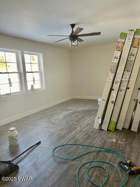 unfurnished room featuring ceiling fan, baseboards, and dark wood-type flooring