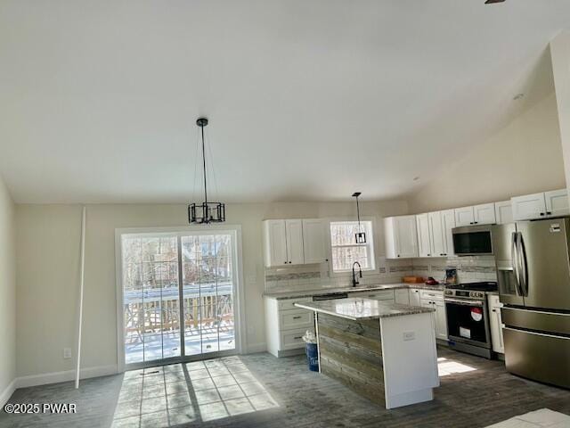 kitchen featuring stainless steel appliances, a center island, white cabinets, and hanging light fixtures