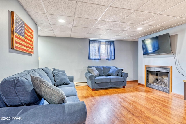 living room with hardwood / wood-style floors, a drop ceiling, and a baseboard radiator