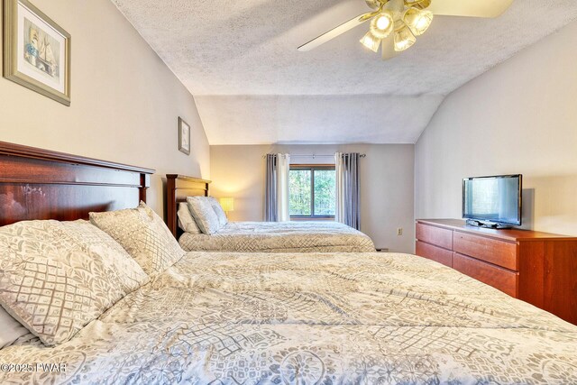 bedroom featuring ceiling fan, lofted ceiling, and a textured ceiling