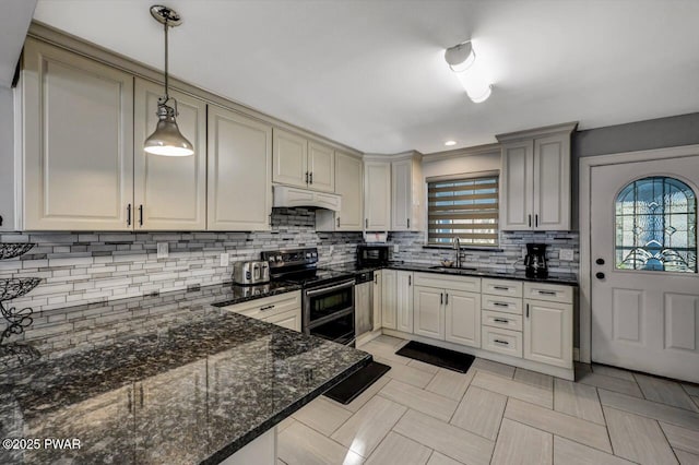 kitchen featuring premium range hood, sink, pendant lighting, dark stone counters, and range with two ovens