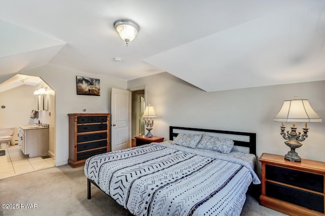 bedroom featuring ensuite bathroom and light carpet