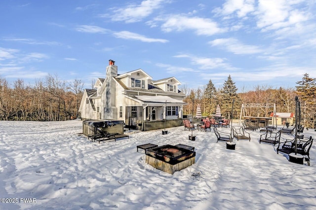 snow covered rear of property with a hot tub