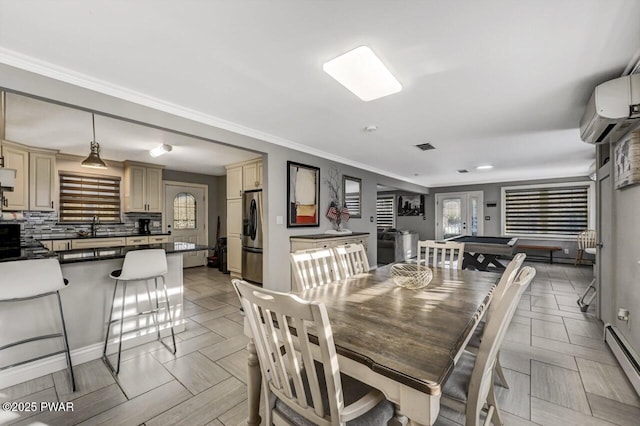 dining room featuring a wall mounted air conditioner, a baseboard radiator, sink, ornamental molding, and french doors