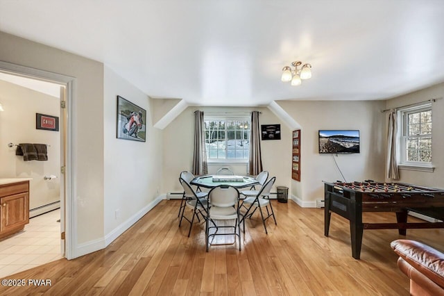 dining space featuring a baseboard radiator, a wealth of natural light, and light wood-type flooring